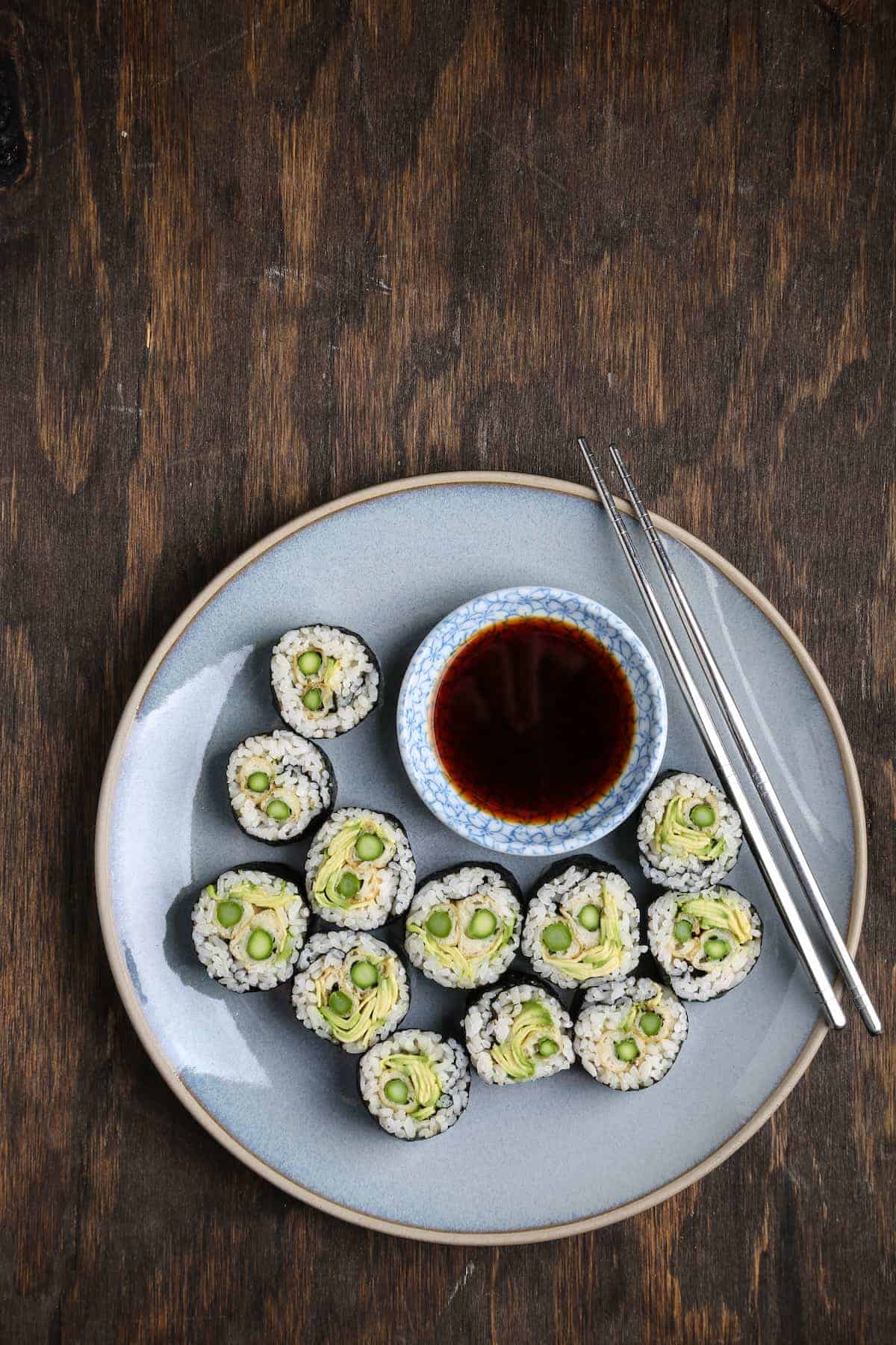 A plate of asparagus tempura and avocado rolls.