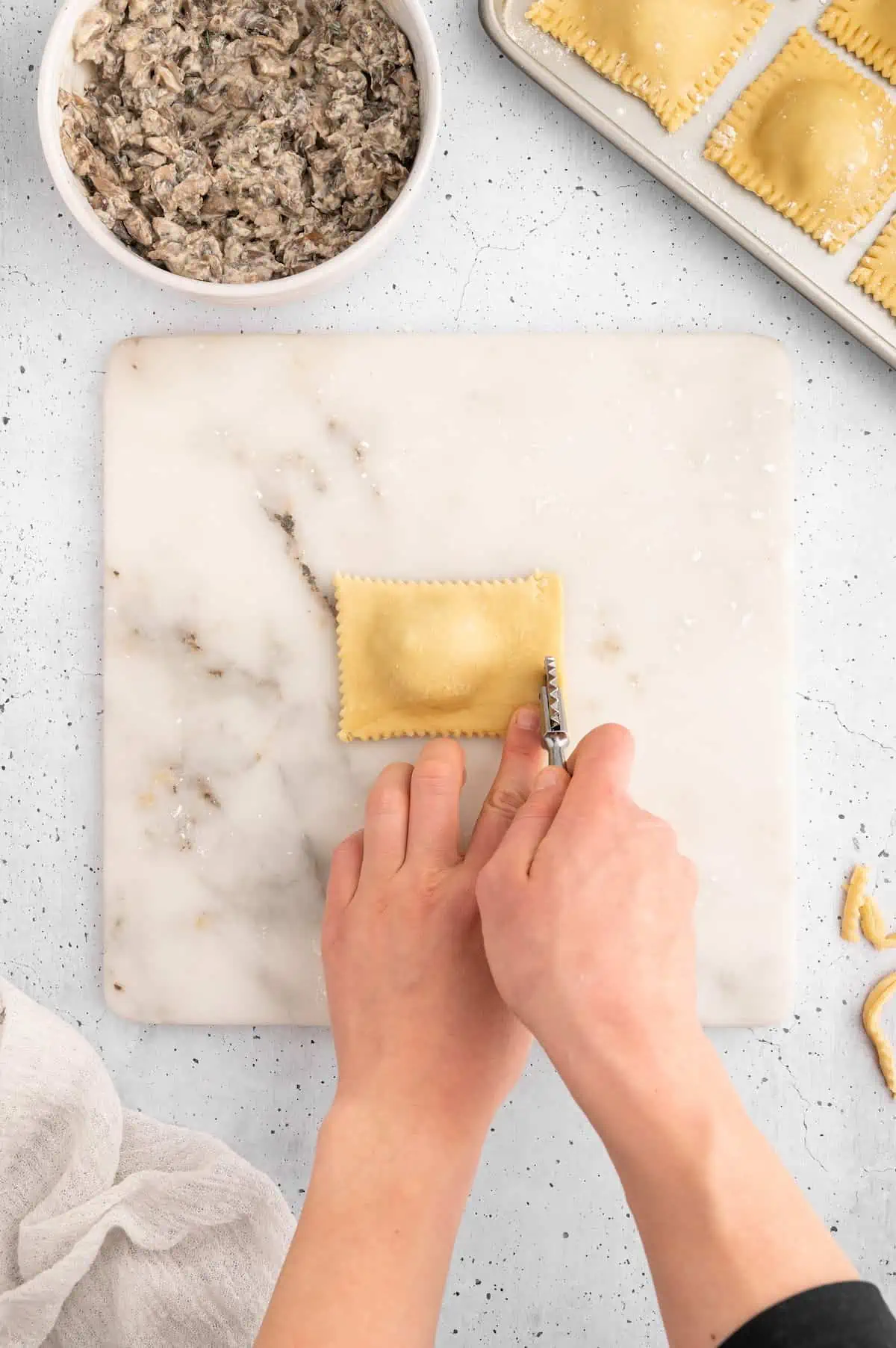 Vegan ravioli being cut into a uniform shape.