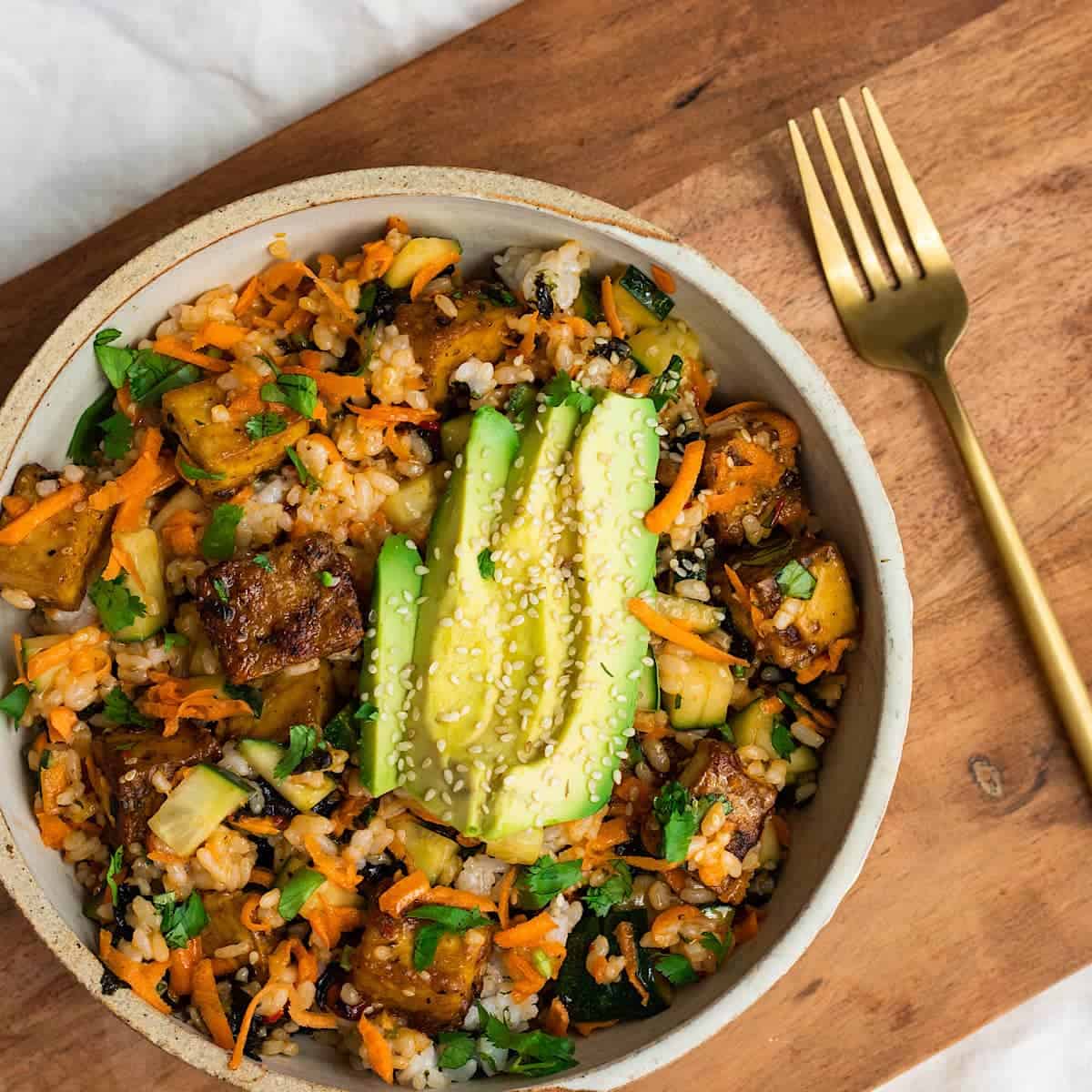 A bowl of rice, tofu and avocado.