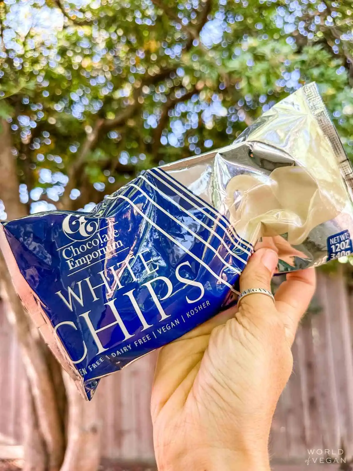 A hand holding up a bag of Chocolate Emporium's dairy-free white chocolate chips.