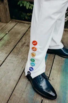 Rainbow bottle caps integrated into bride's white wedding suit with vegan shoes.