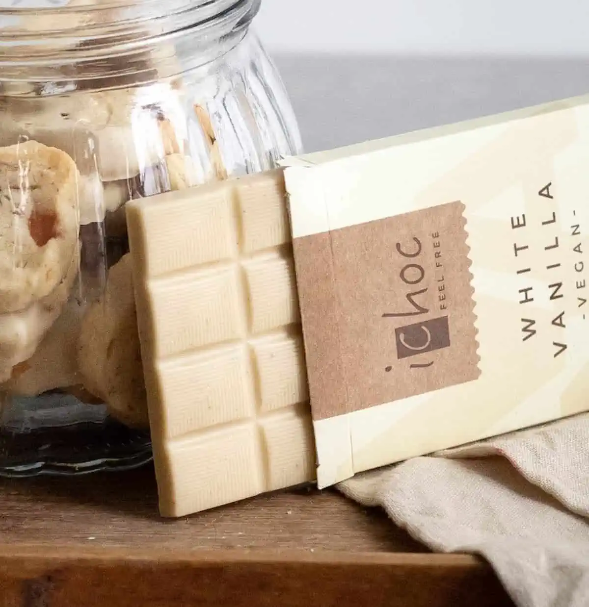 A bar of vegan iChoc white chocolate next to a jar of cookies.