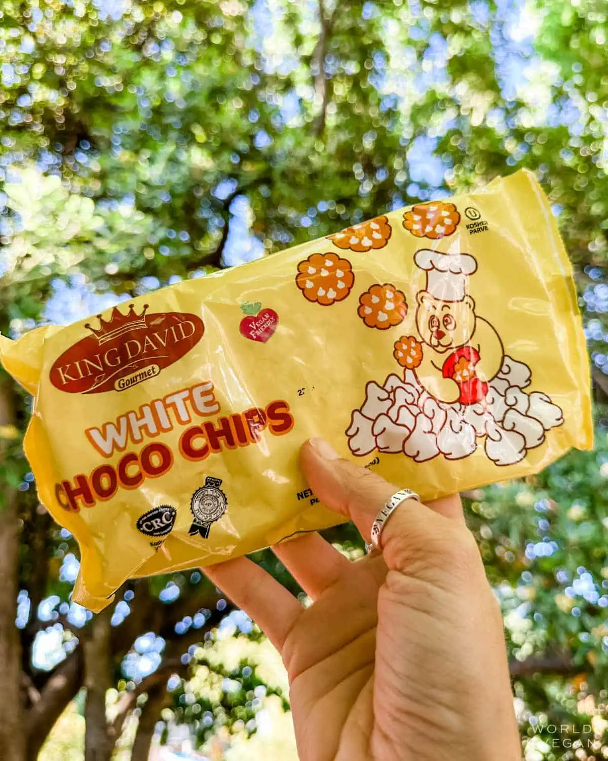 A hand holding up a bag of King David's vegan white chocolate chips.