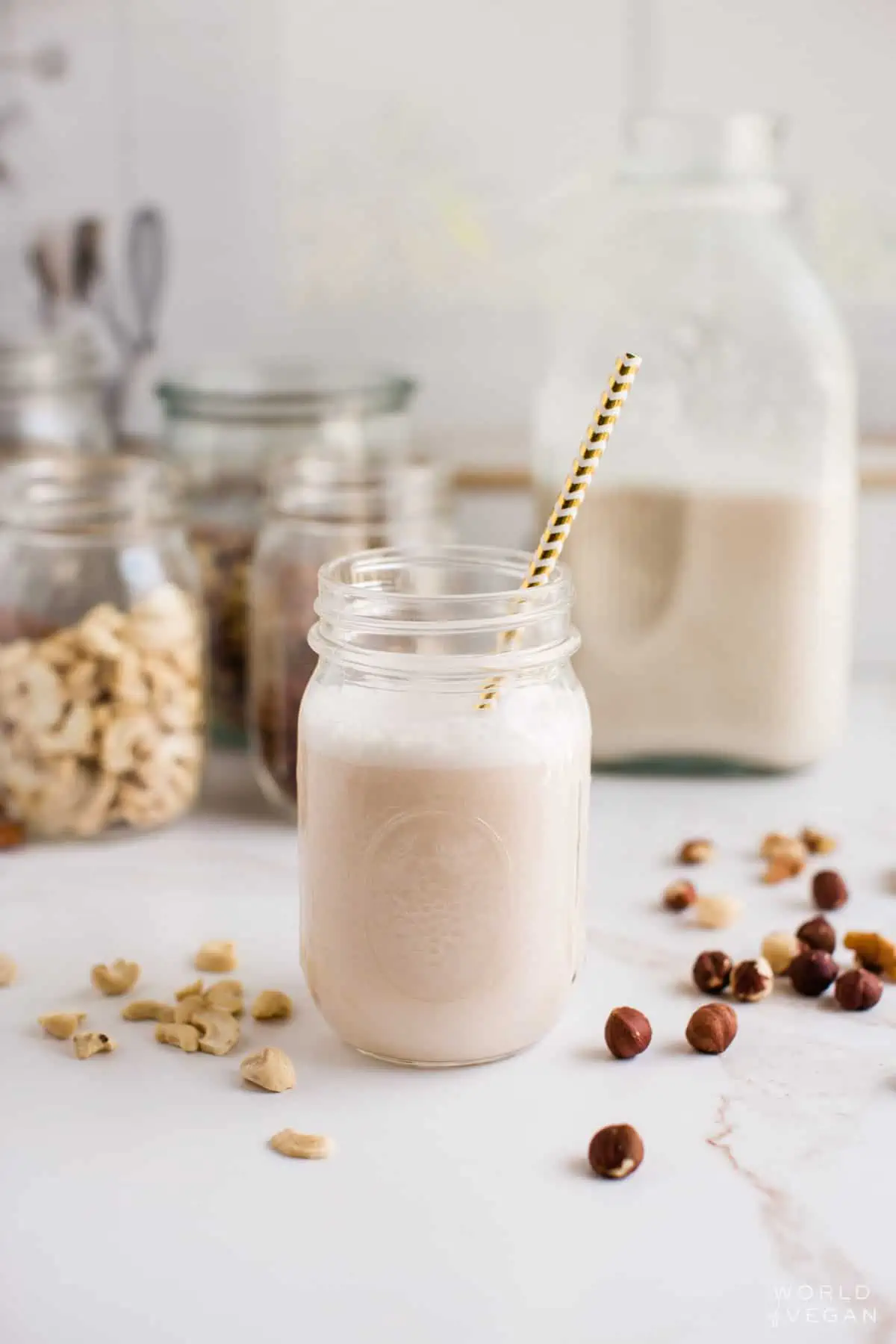 Plant-based milk in a mason jar surrounded by raw nuts.
