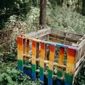 DIY colorful rainbow painted compost pile box made from wood.