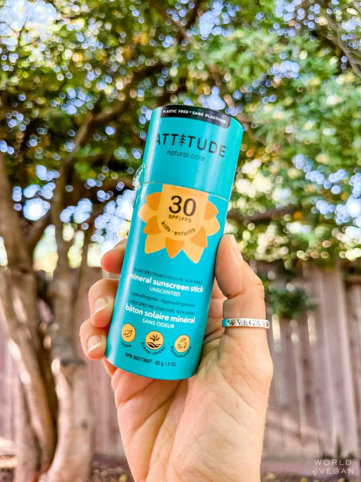 Holding out a cardboard turquoise tube of zero waste compostable plastic-free face sunscreen from Attitude. 