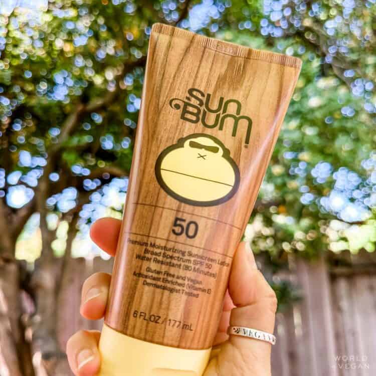 Woman holding out a tube of vegan sunscreen from the popular brand Sun Bum.