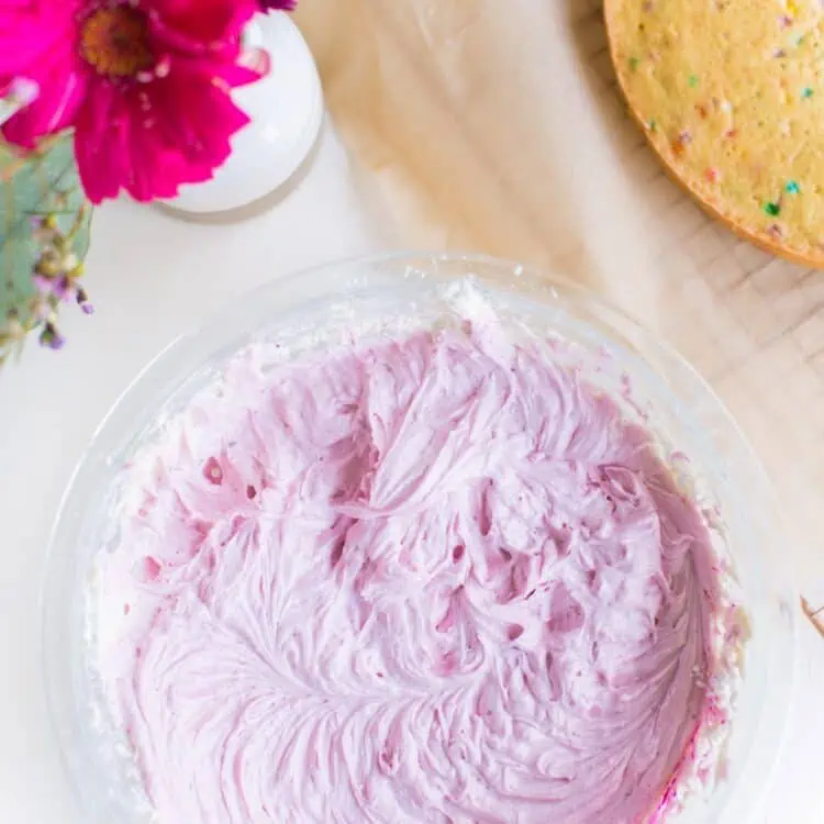 A glass bowl of vegan frosting colored pink for cake decorating.