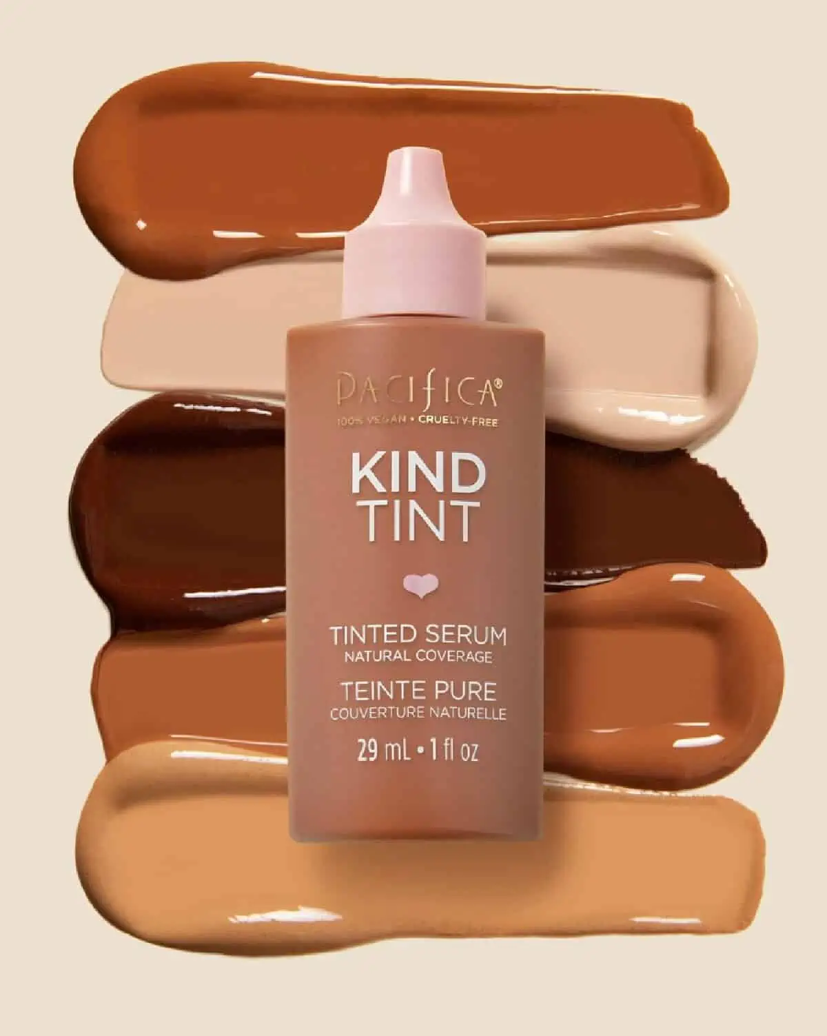 A small squeeze bottle with pink top containing Pacifica Beauty's Kind Tint foundation laying atop of five swatches of foundation colors.