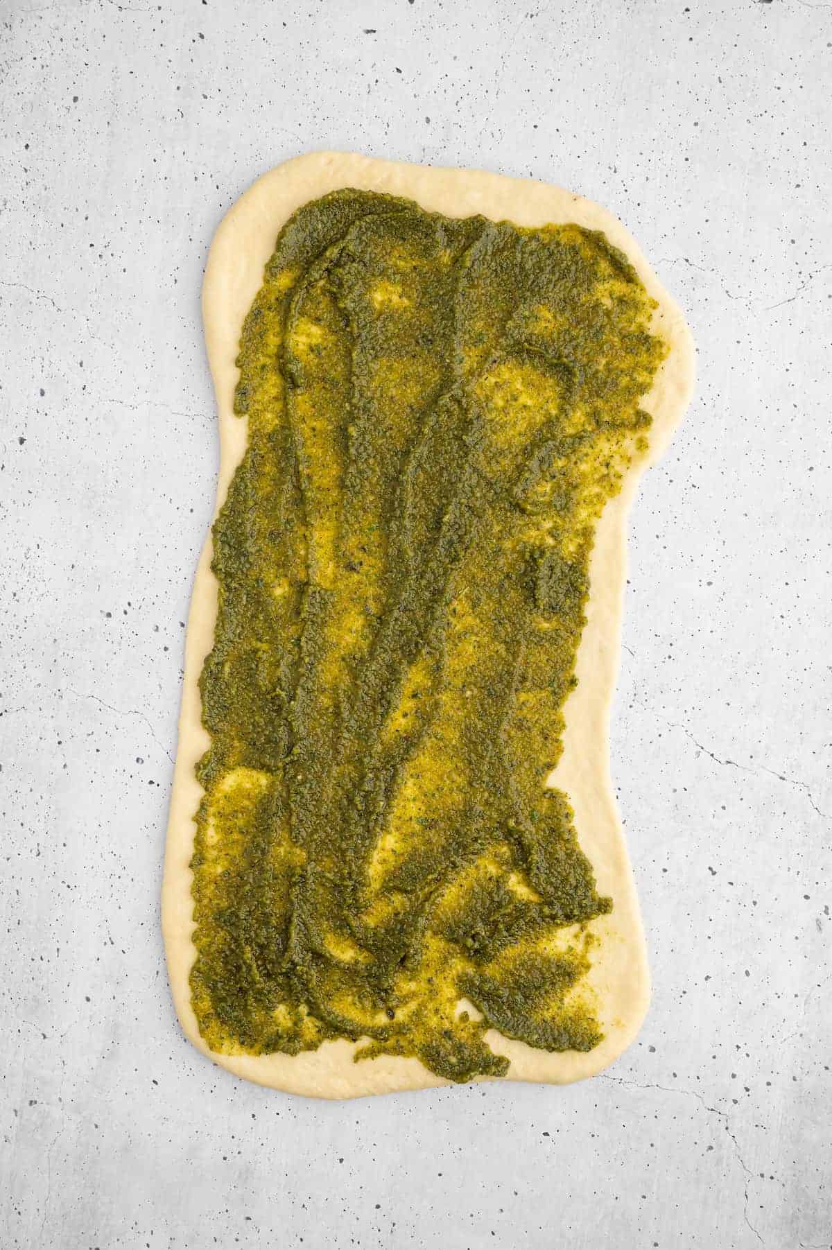 Walnut pesto spread onto a piece of rolled out dough.
