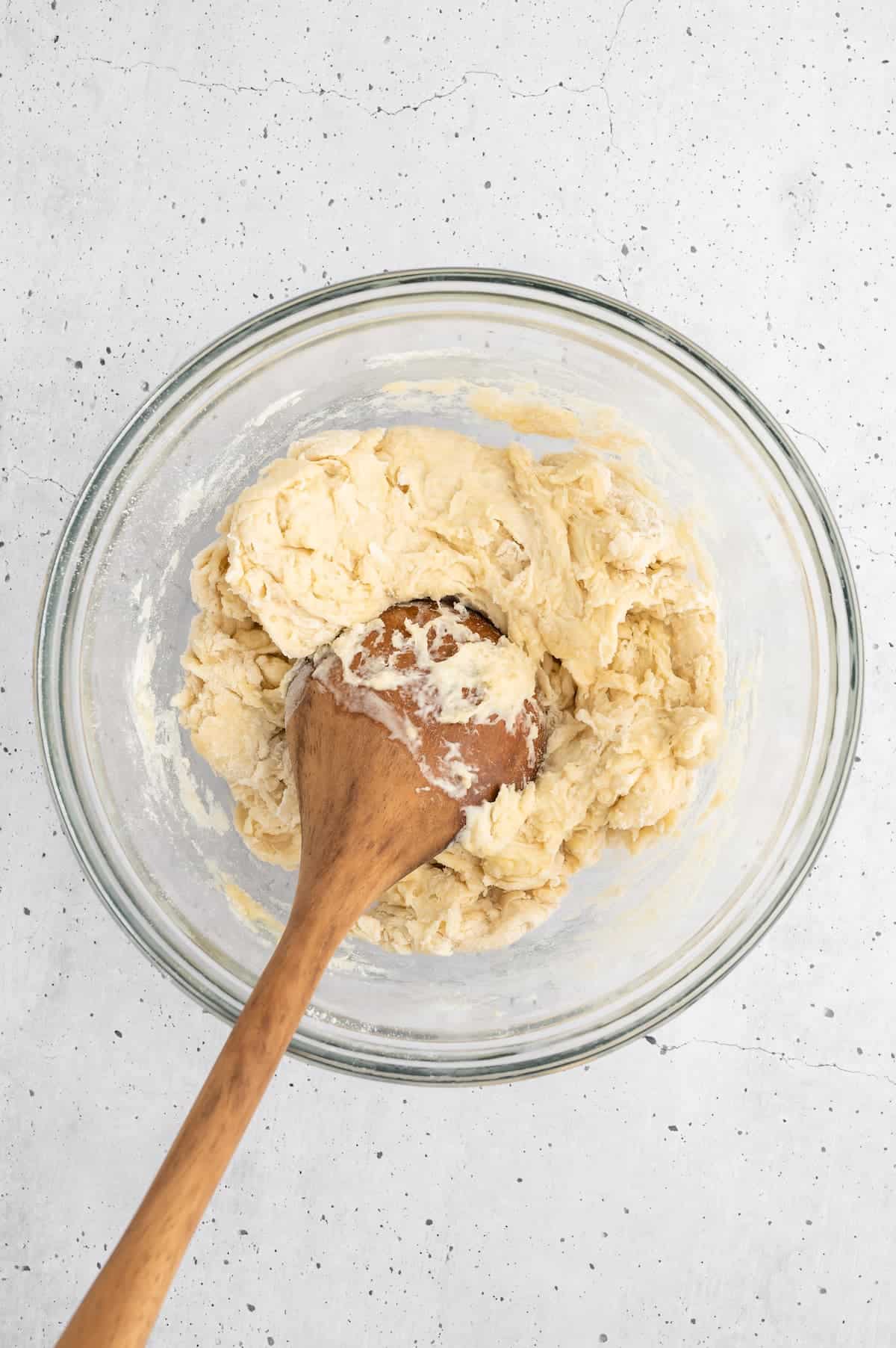 Pest bread dough in a bowl with a wooden spoon.