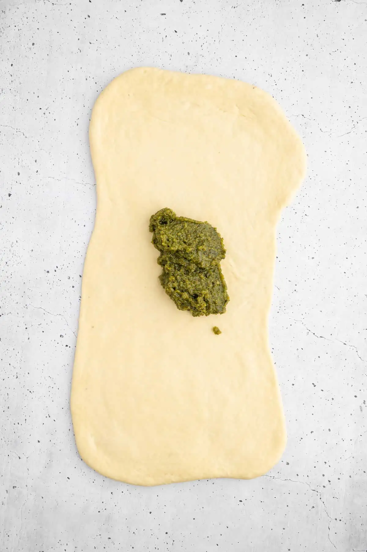 A dollop of vegan walnut pesto on a rolled out sheet of dough.