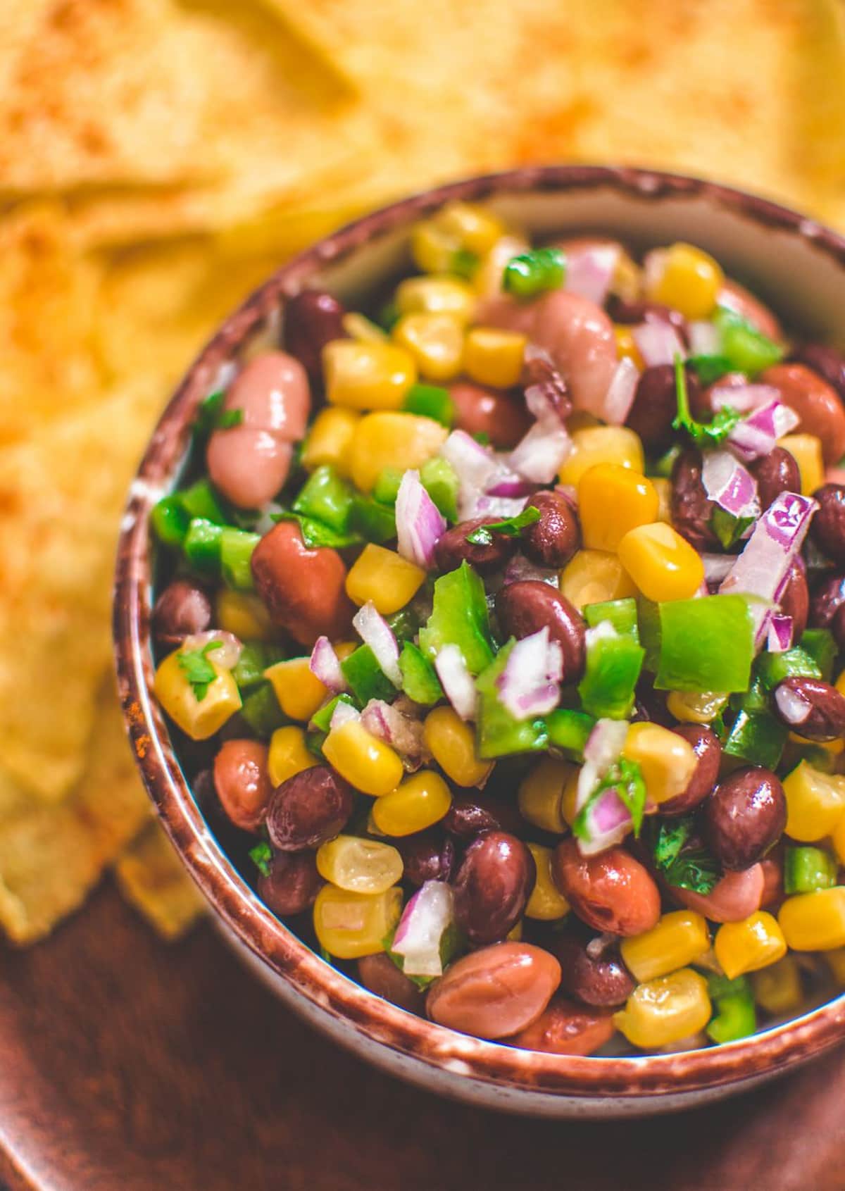 A bowl of vegan Texas caviar with beans, onions, corn, and colorful vegetables.