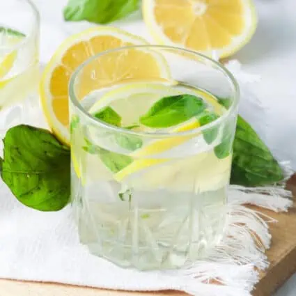 A glass of basil lemon-infused water on a countertop.