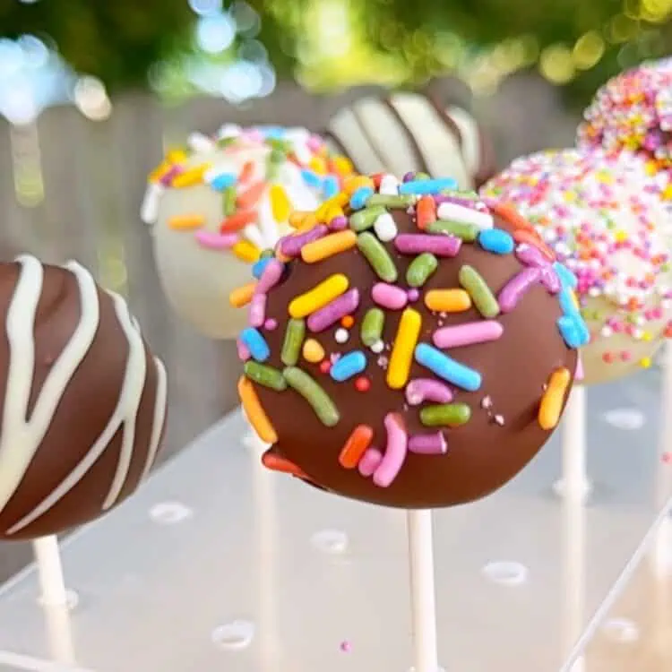 Vegan cake pop outside with rainbow sprinkles, with a no-bake cookie dough cake base.