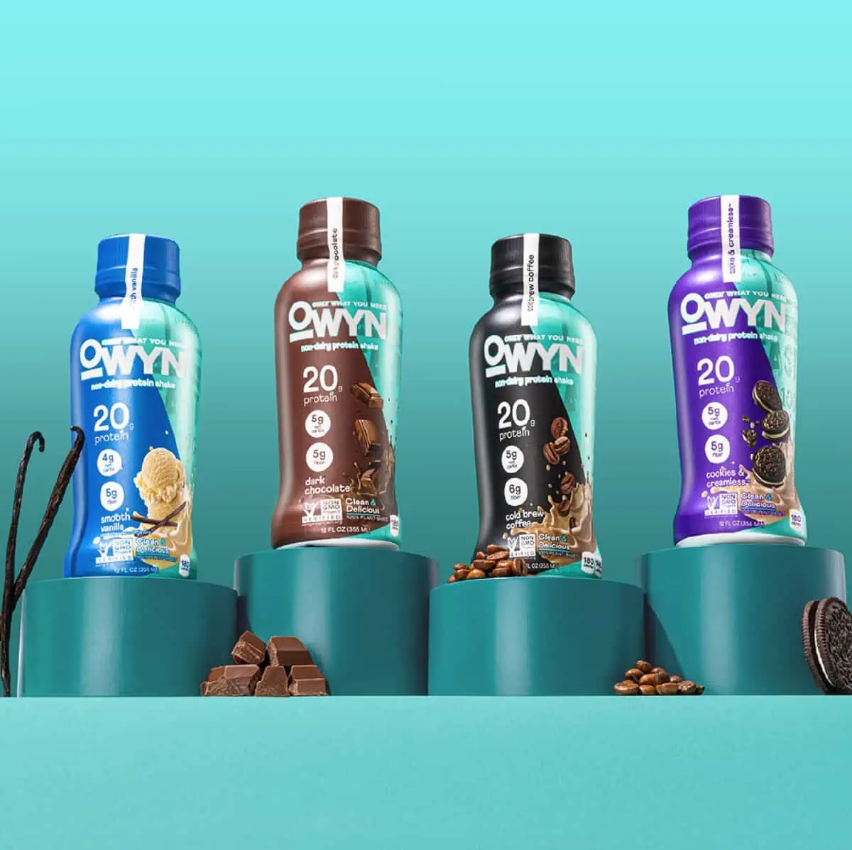 Four bottles of Owyn non-dairy protein shakes in four different flavors against a teal background.