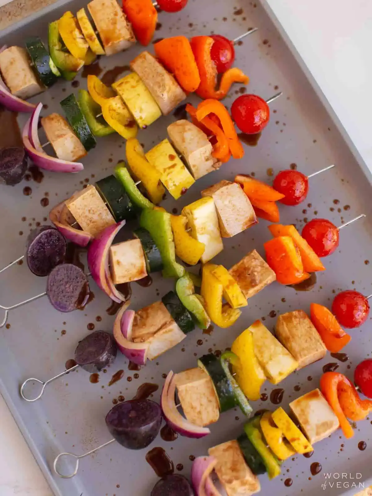 Vegan tofu kabobs on a baking tray, covered with kebab marinade.