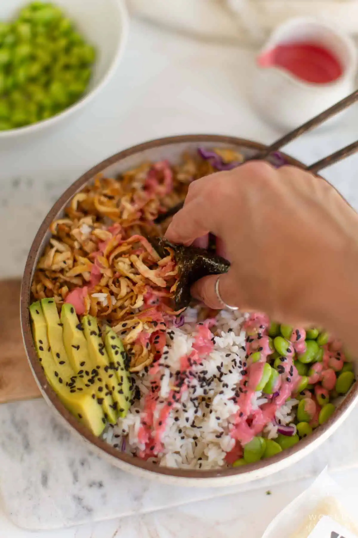 Scooping up shredded tofu from the bowl with snack pack roasted nori seaweed sheets.