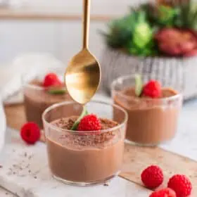 A hand holding a spoon over a jar of silken tofu mousse.
