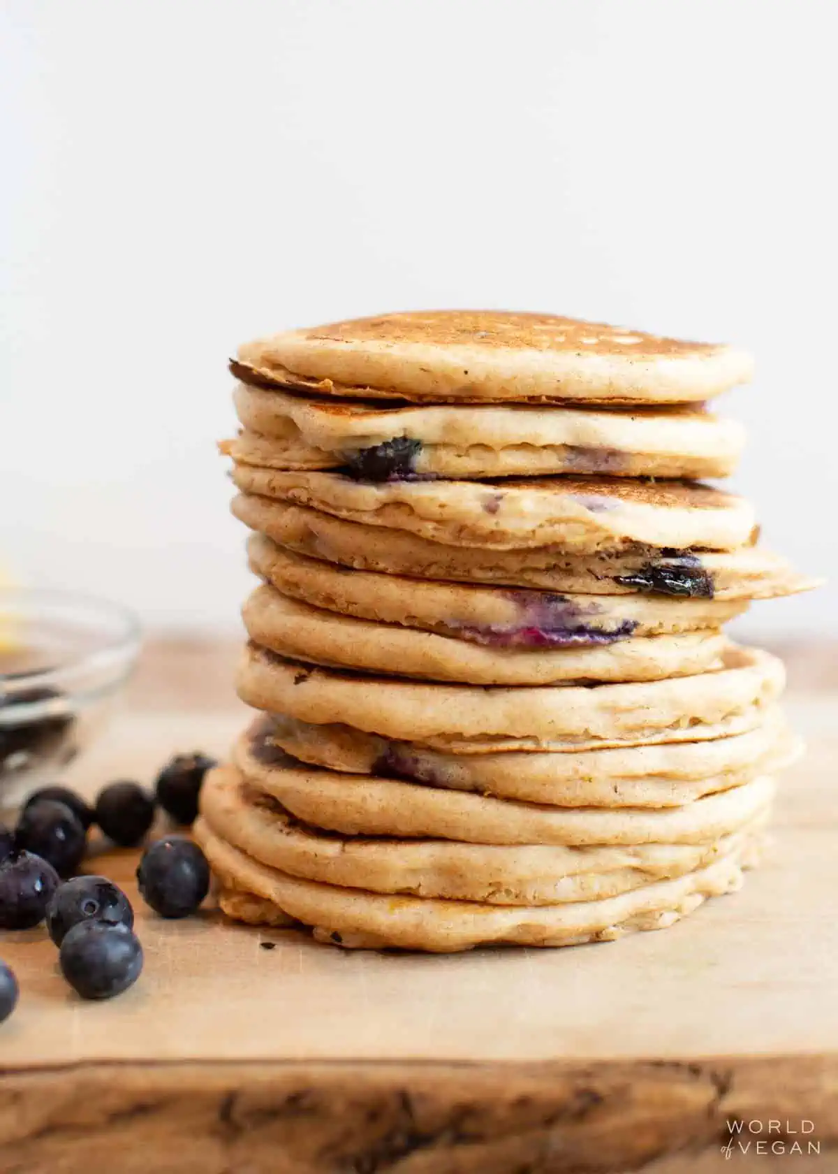 A stall stack of vegan blueberry pancakes, with additional blueberries scattered around.