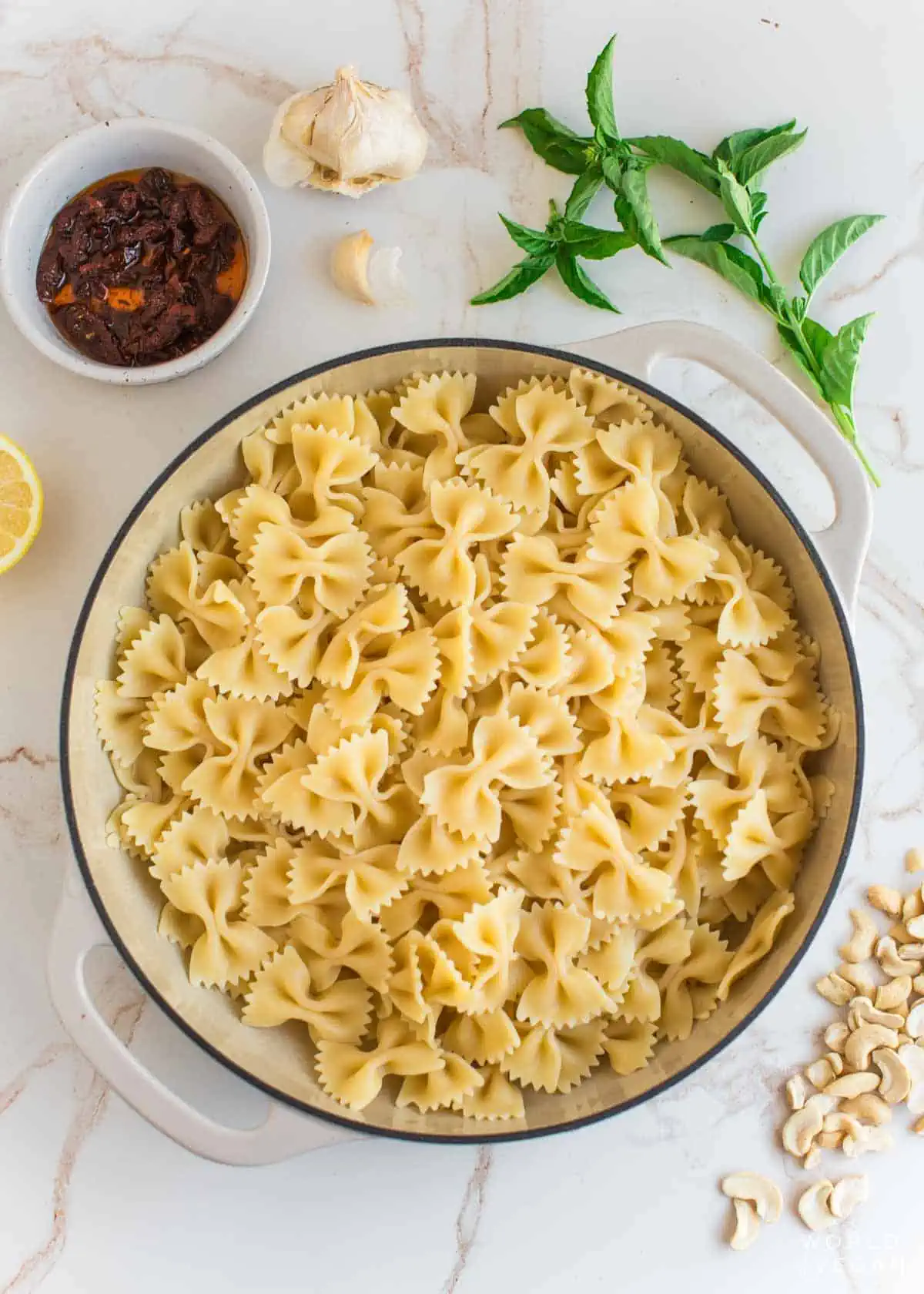 Cooked pasta next to sun dried tomato sauce ingredients.