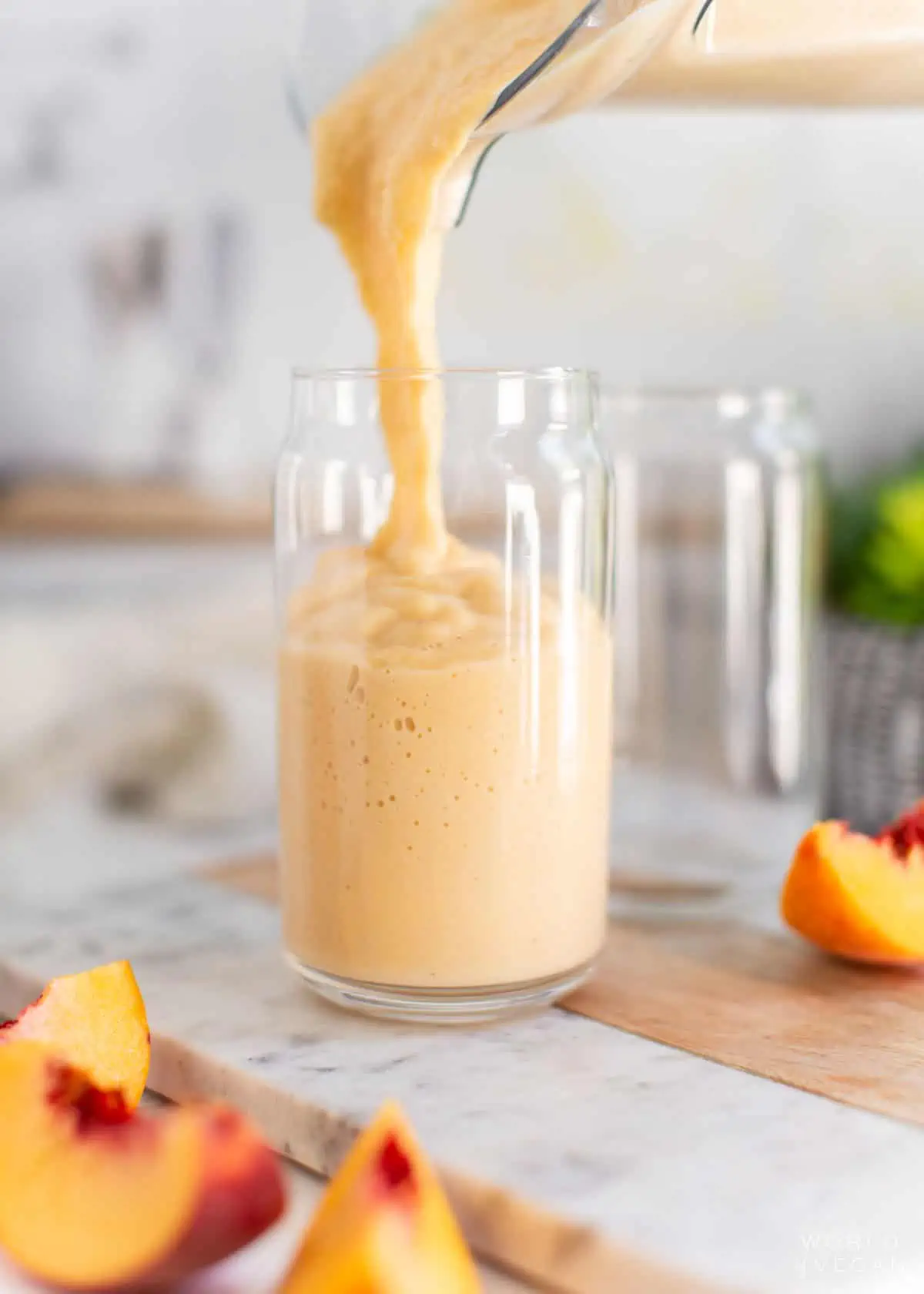 Pouring the peach and banana smoothie into a glass.
