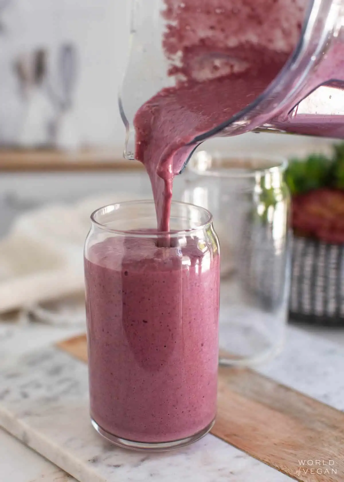 Blender pitcher pouring silken tofu smoothie into a glass.