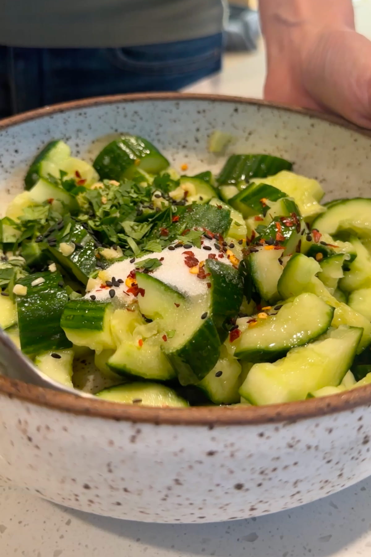 The ingredients for the dressing added to the bowl of chopped cucumber.