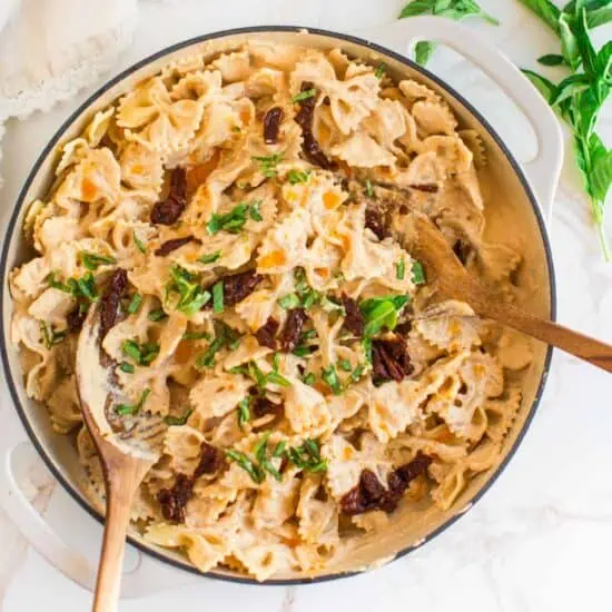 Sun dried tomato sauce mixed with pasta in a large dutch oven.