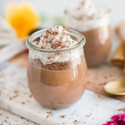 Tofu chocolate pudding in small jars, topped with vegan whipped cream.