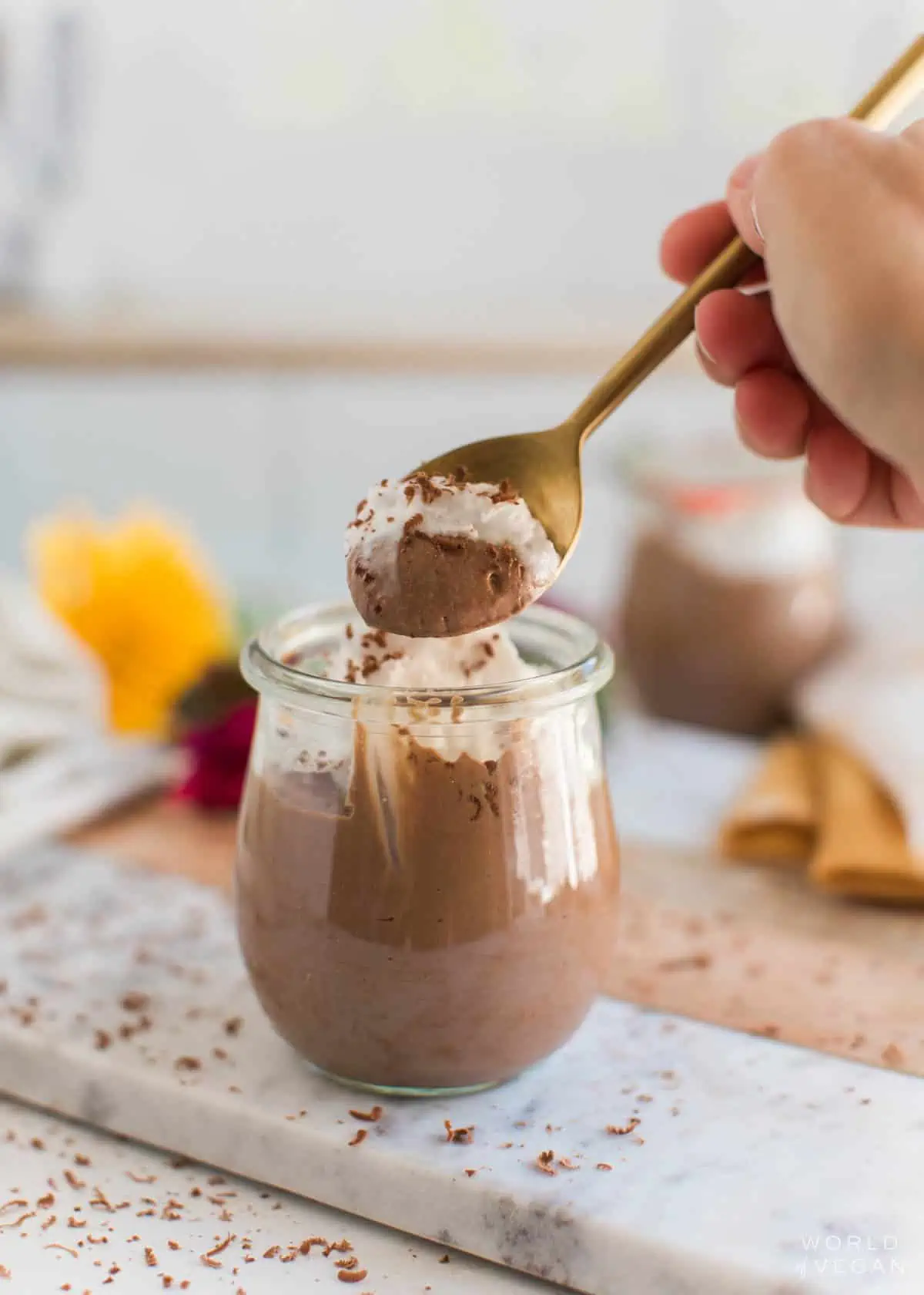 Hand scooping up a bite of vegan chocolate pudding with a spoon.