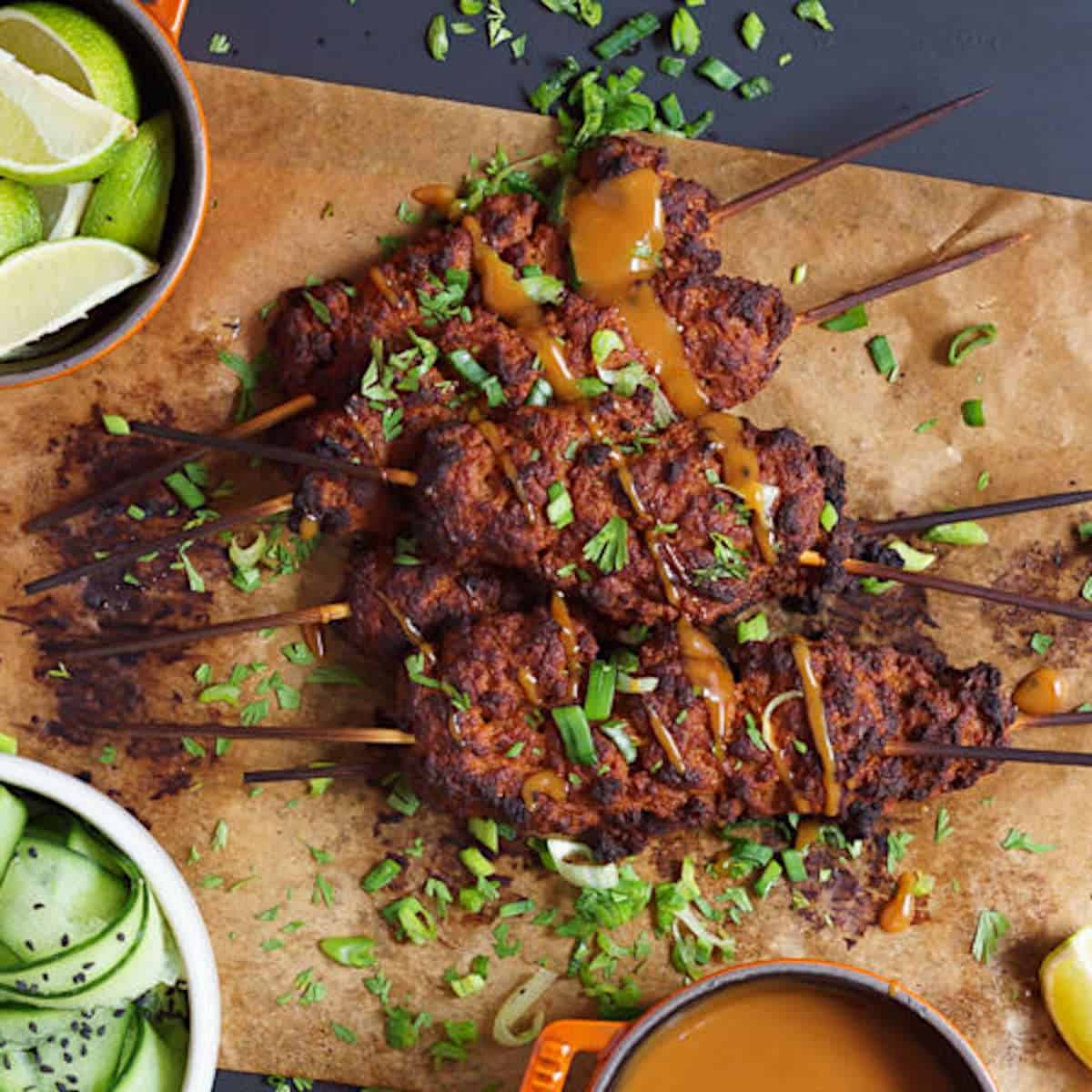 Seitan kebabs on wooden skewers, drizzled with peanut sauce.