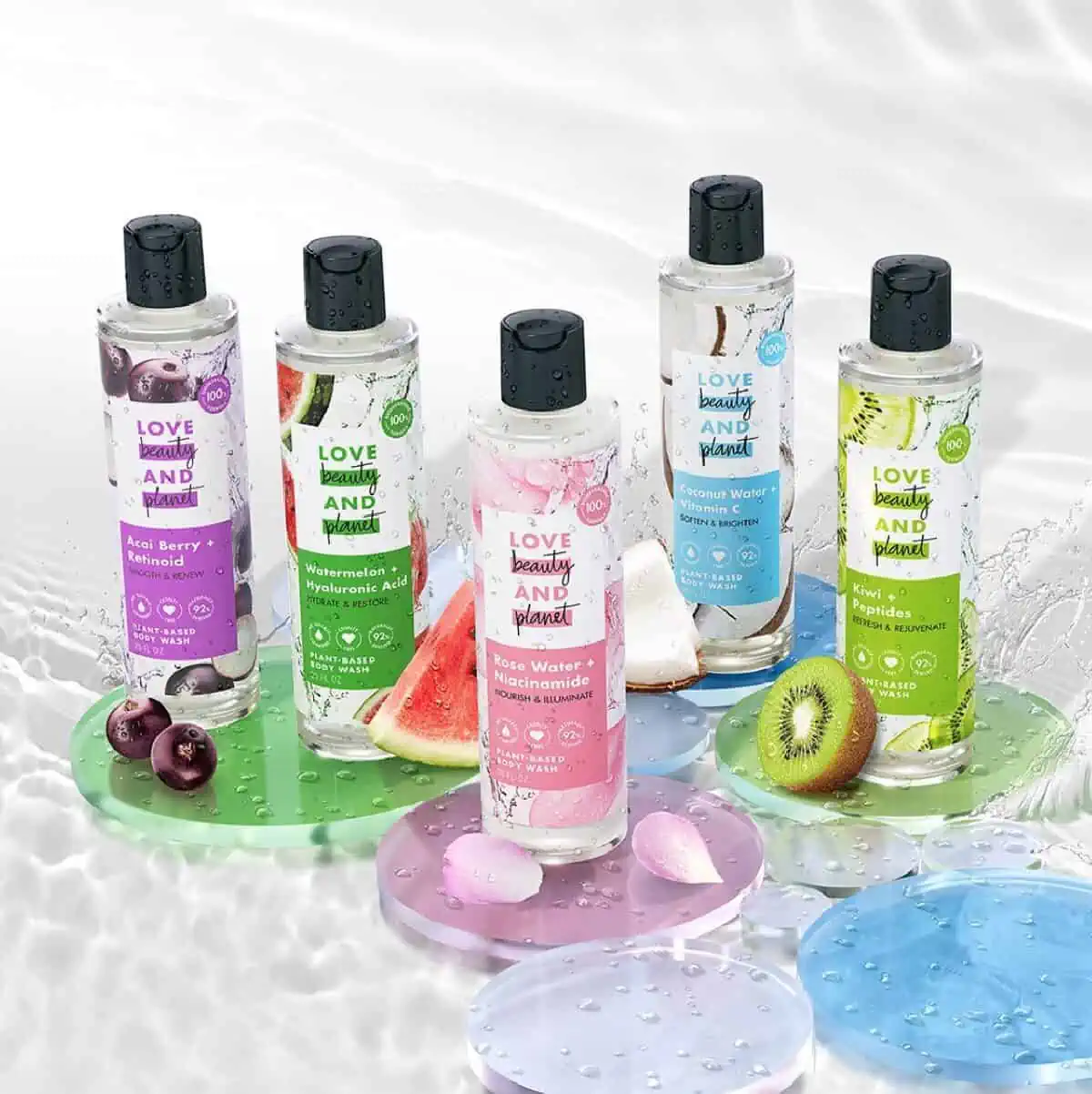 Five clear and colorful bottles of Love Beauty and Planet plant-based body washes on translucent colorful circles and a watery background. 