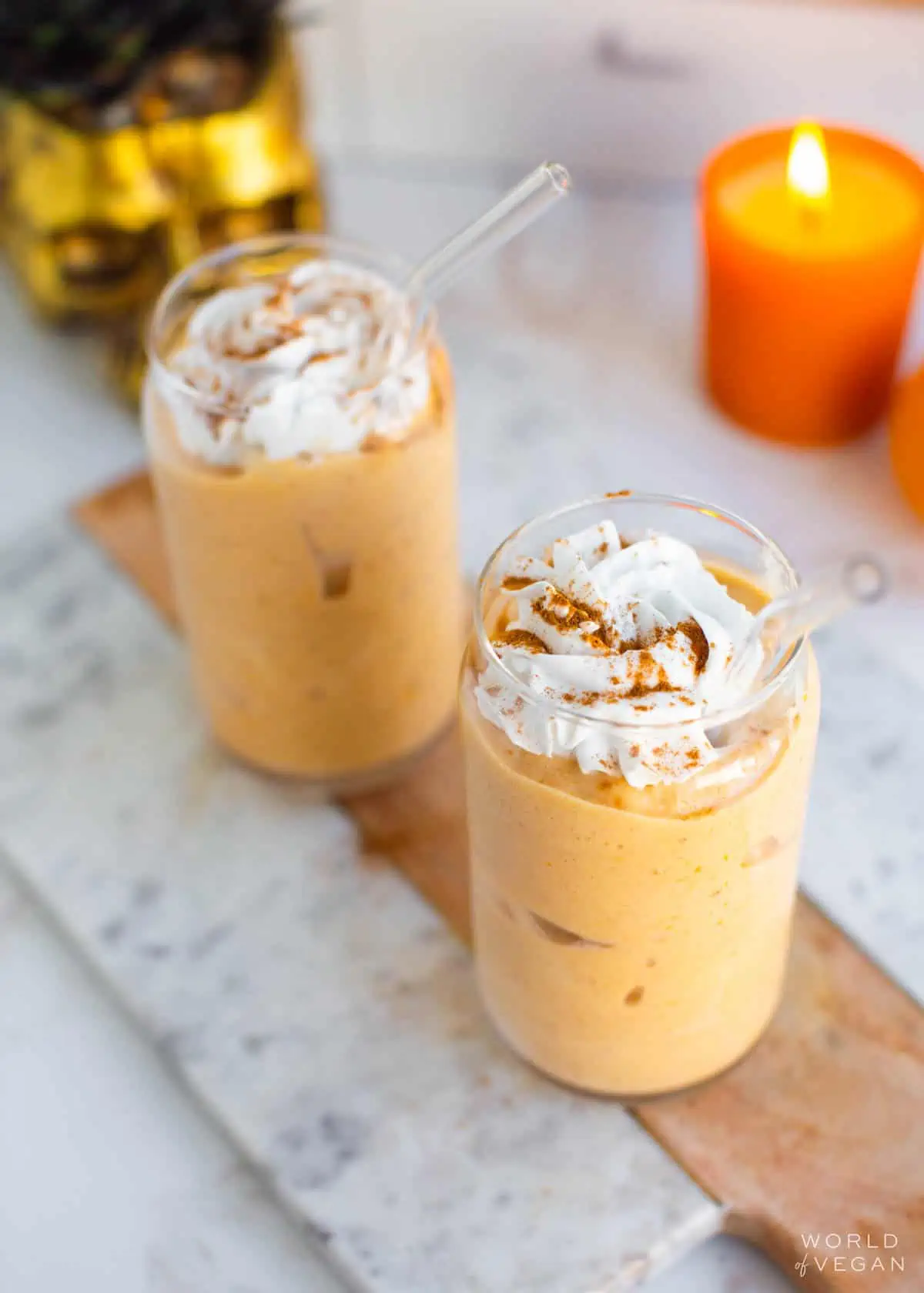 Two glasses of pumpkin pie milkshake topped with vegan whipped cream.