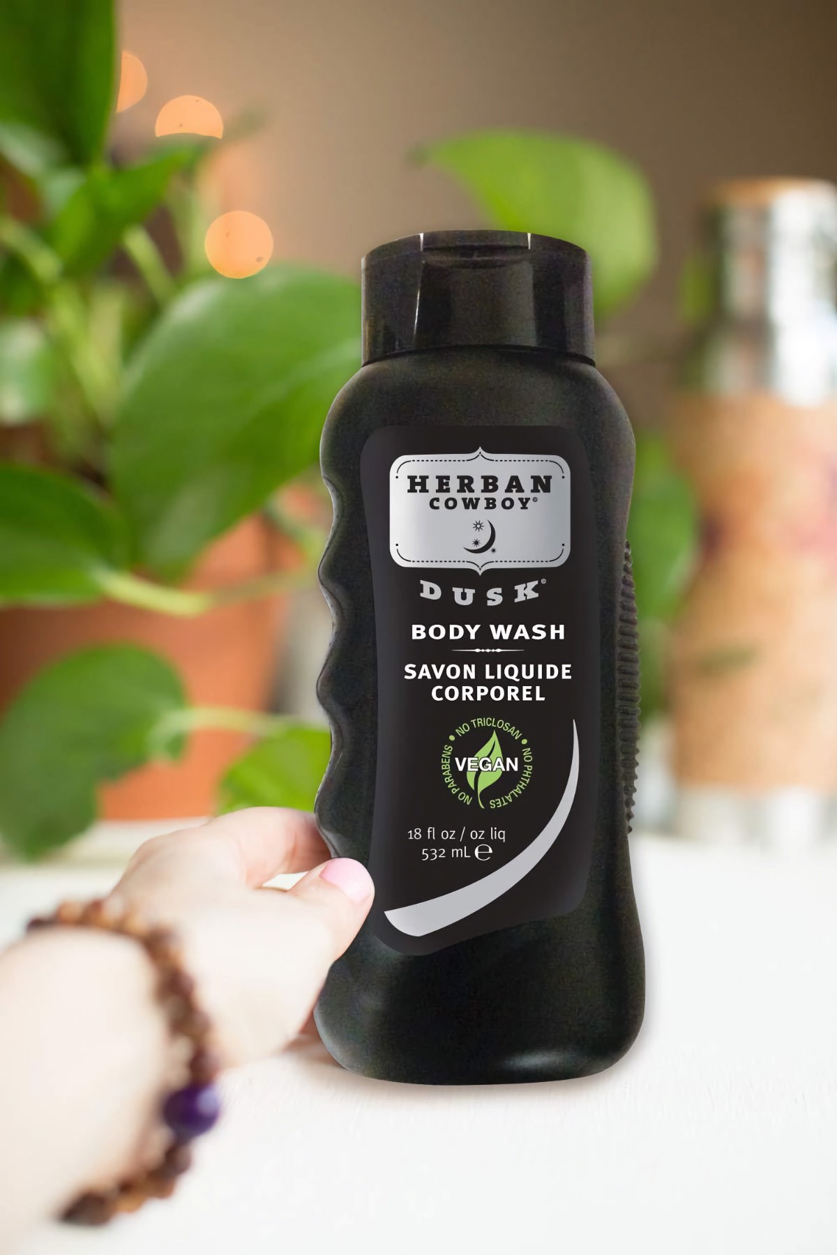 Vegan hand holding a bottle of Herban Cowboy's men's body wash.