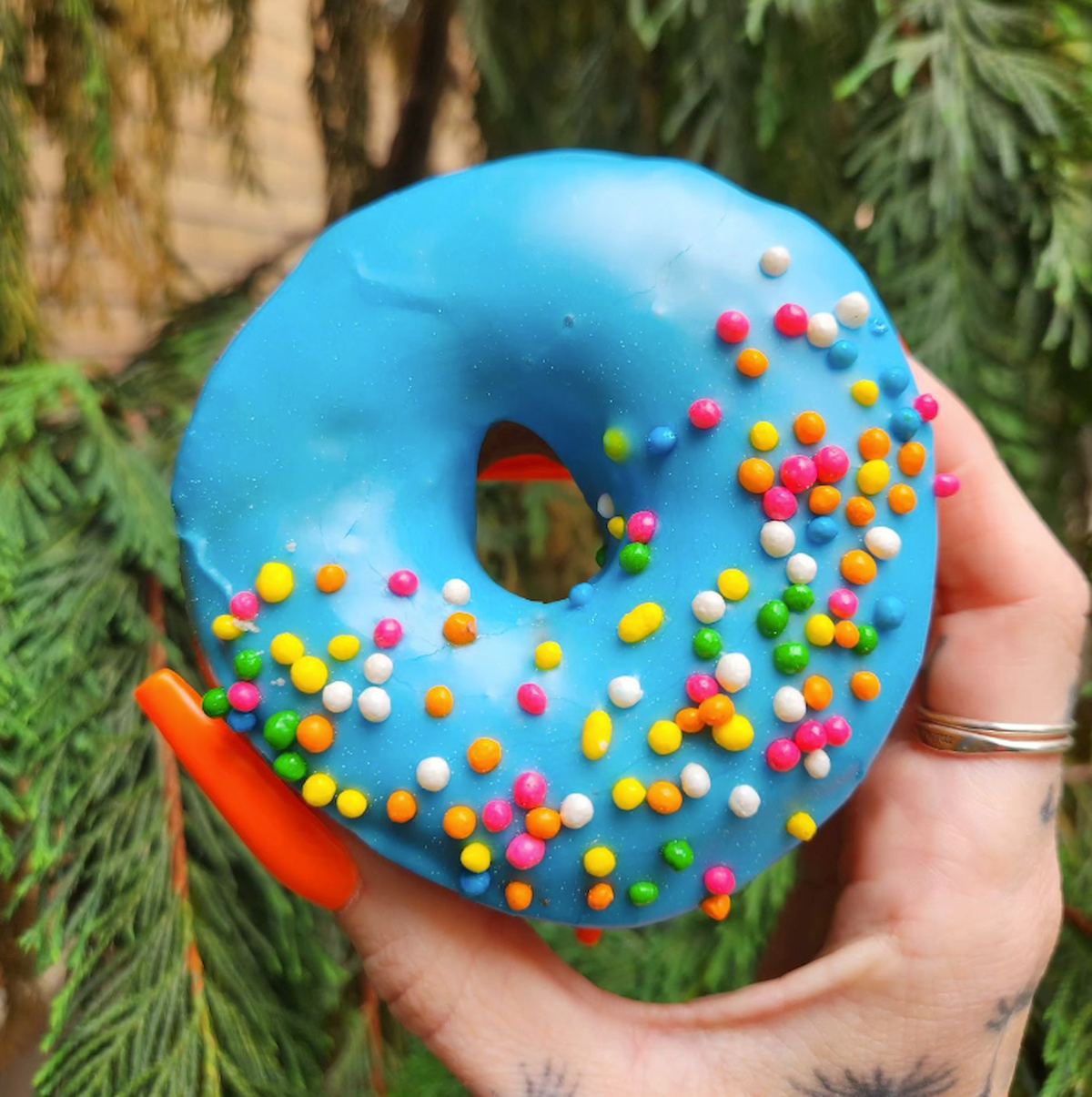 A hand holding a bubble gum flavored vegan donut.
