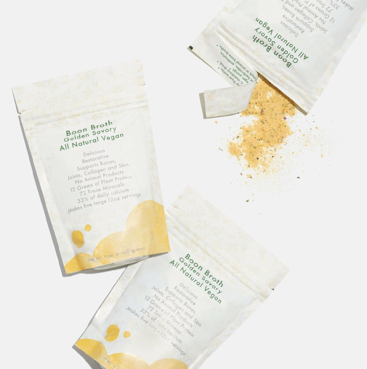 Two unopened and one opened white pouch of vegan boon broth by Ecobella on a white background. 