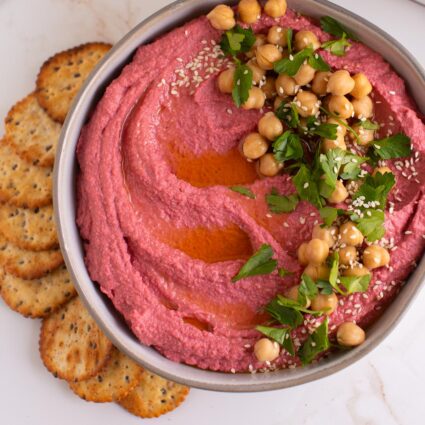 Pink Hummus made with beet and topped with chickpeas served with crackers.