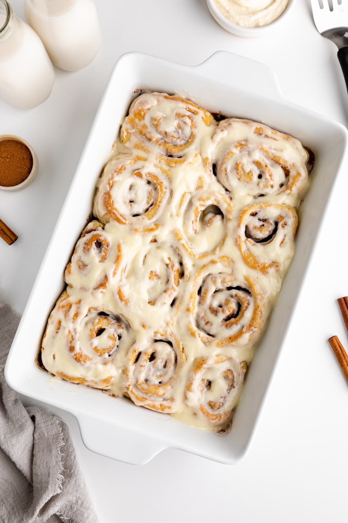 Vegan cinnamon rolls in a baking dish covered with frosting.