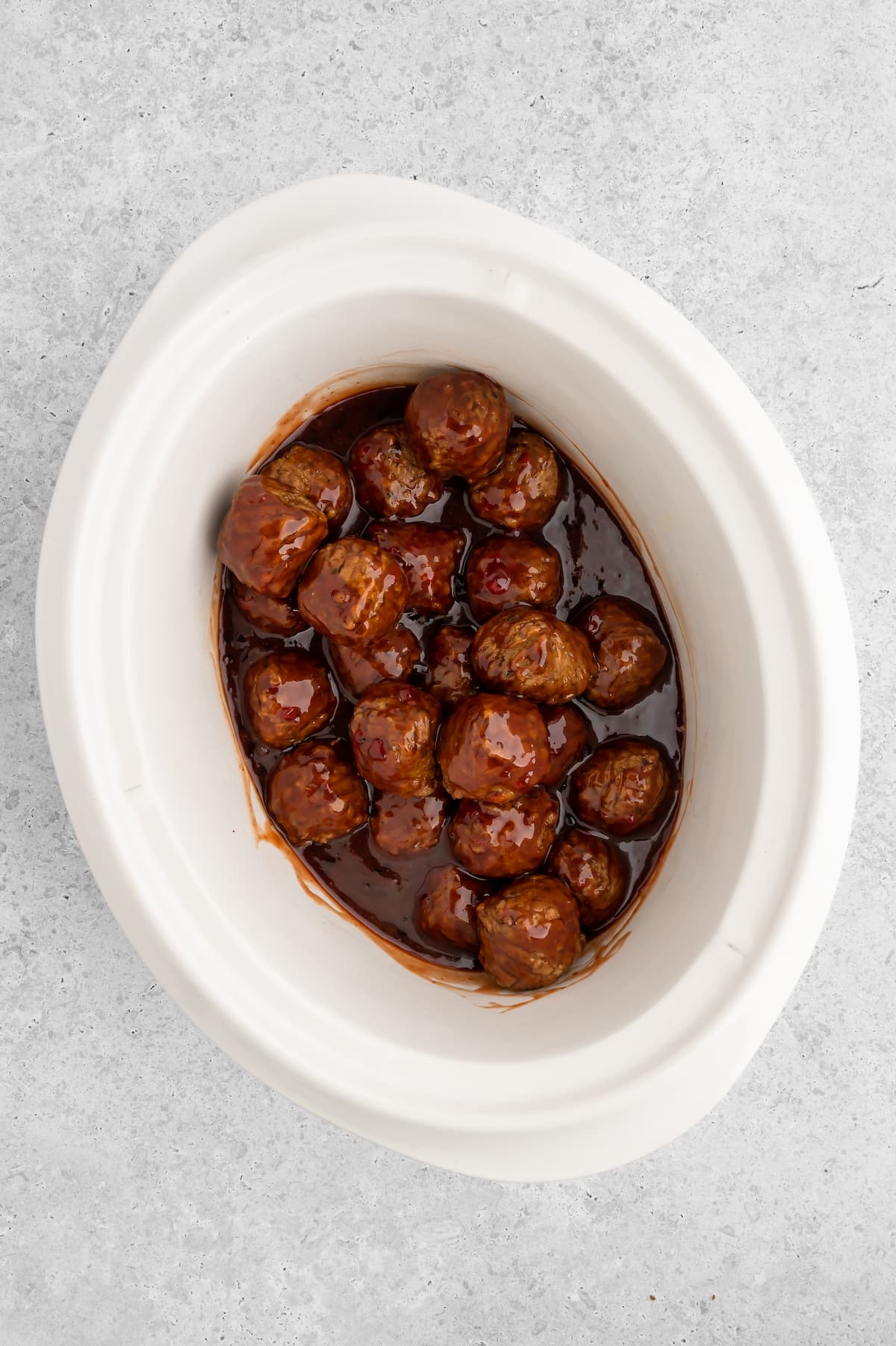 The vegan meatballs added to a slow cooker and all mixed together with the jelly barbecue sauce.