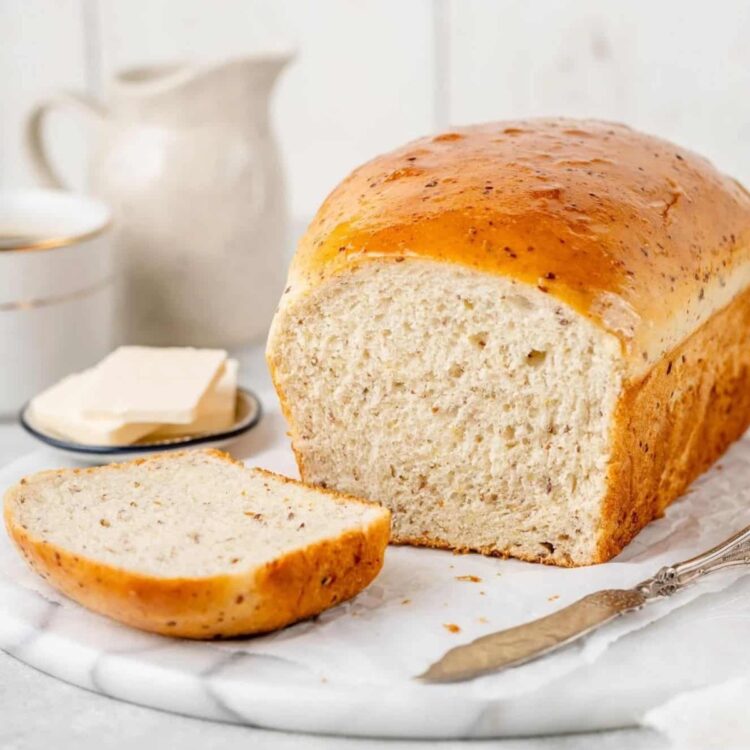 Vegan bread load sliced on a plate and cutting board served with dairy-free butter.