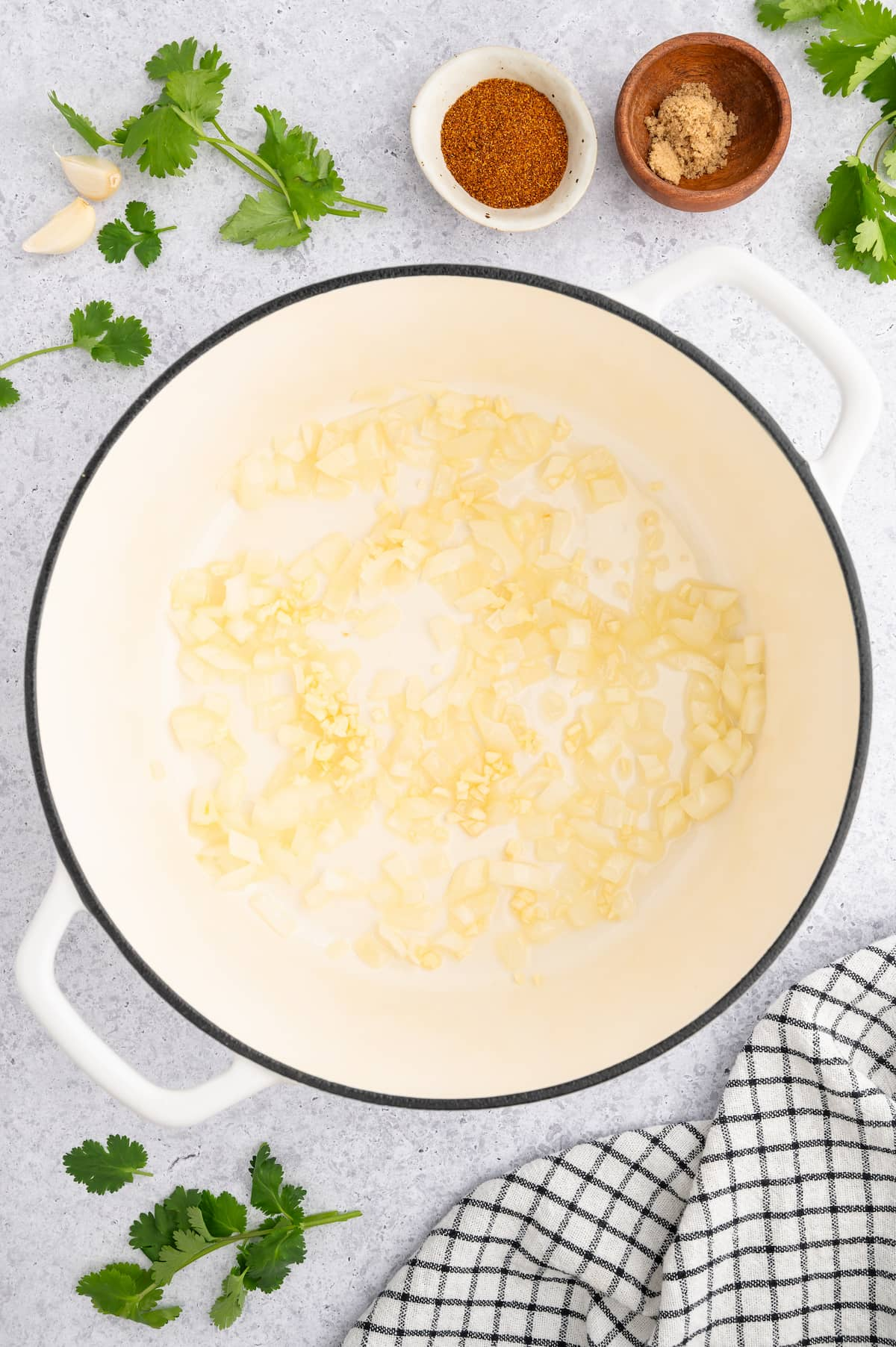 Diced onion and garlic sauteeing in a large Dutch oven pot.