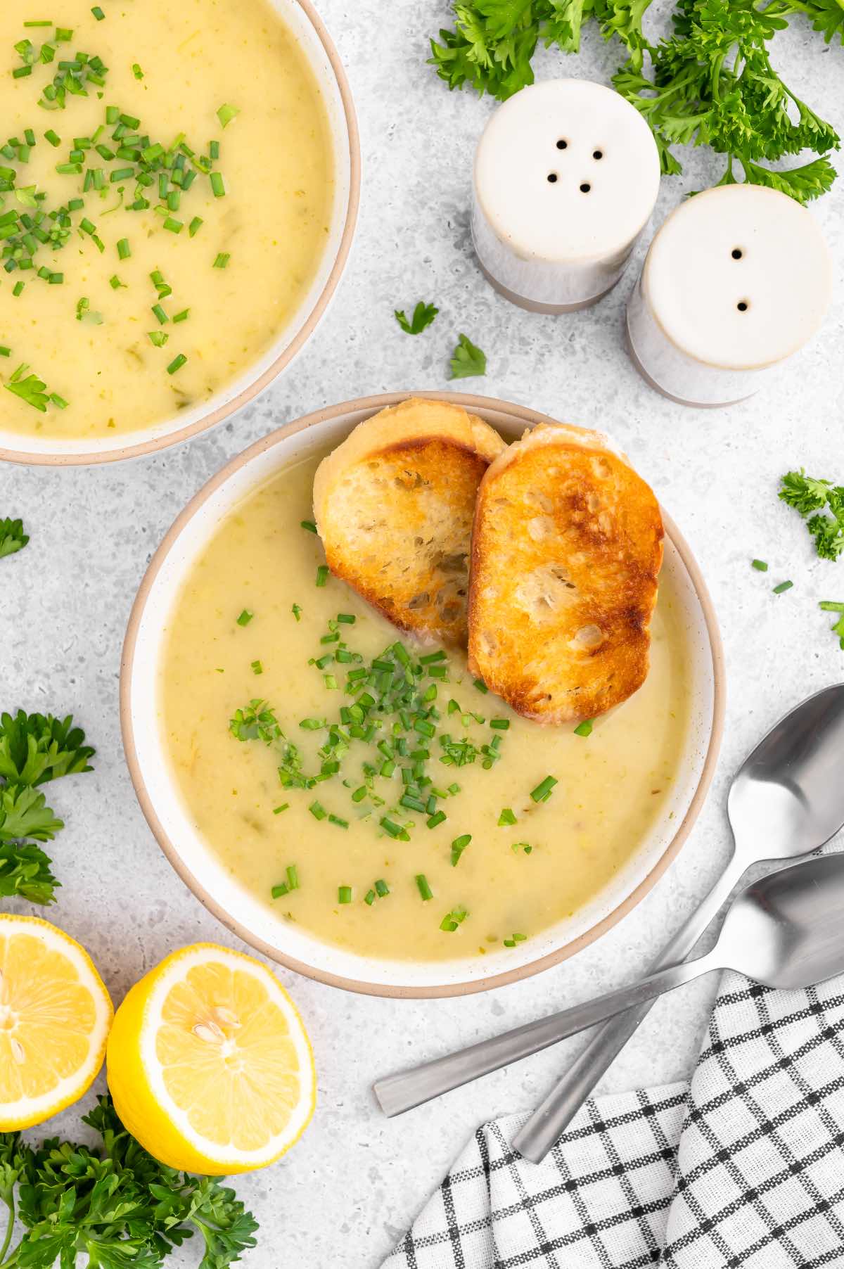 Creamy bowl of potato leek soup with crusty bread and a lemon on the side.