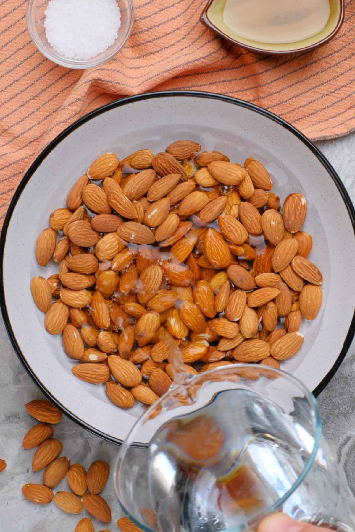 Water being poured into a bowl of almonds.