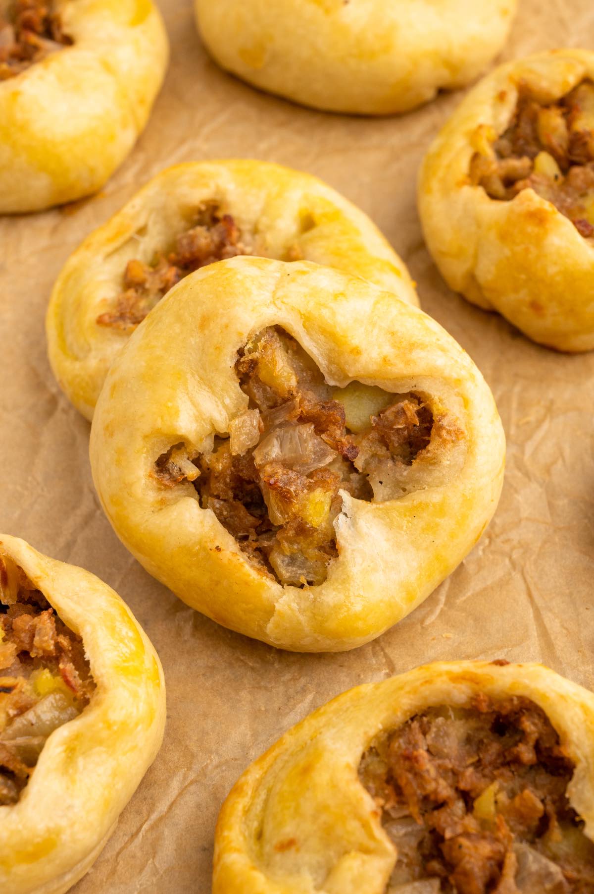 Round vegan knishes on a baking tray with parchment paper.