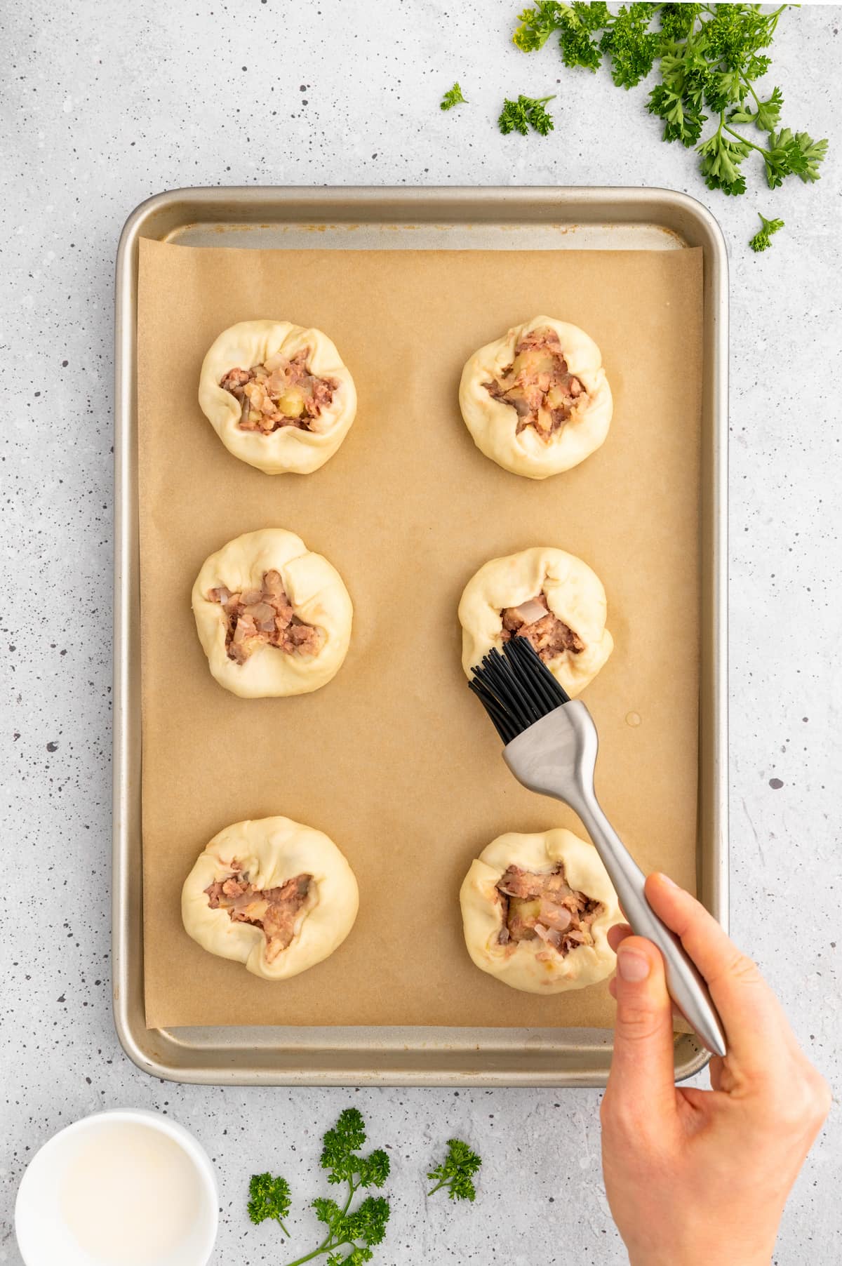 Brushing the outside of the knishes with an "egg wash."