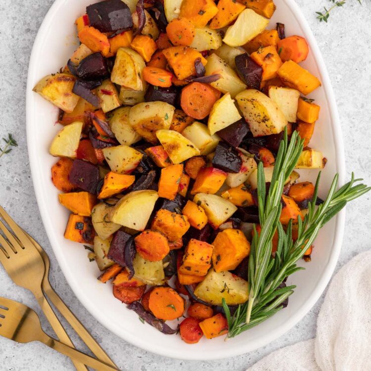 A platter of roasted fall vegetables including potatoes, beets, carrots, and rosemary garnish.