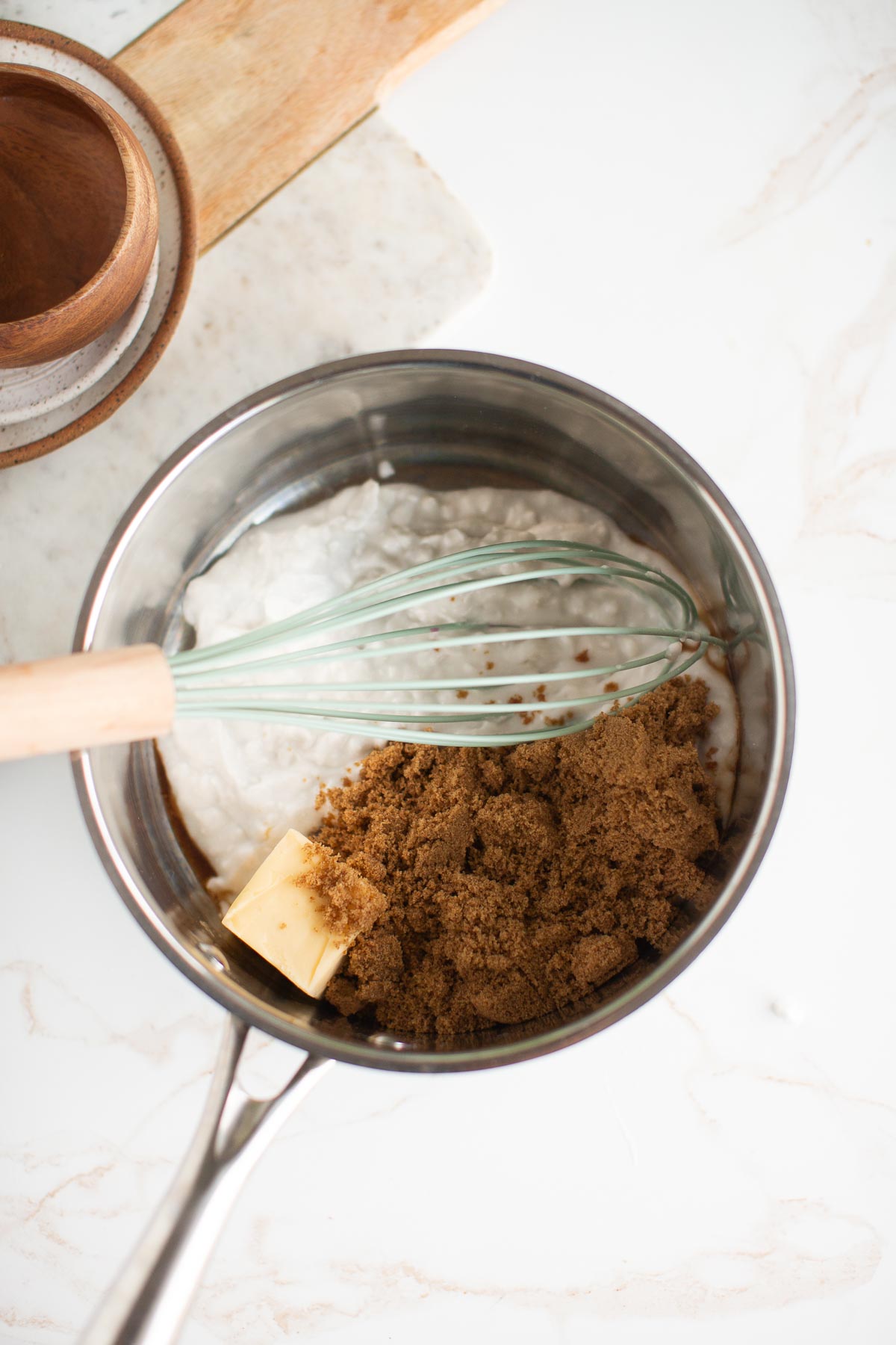 Ingredients for vegan caramel in a saucepan with a whisk.