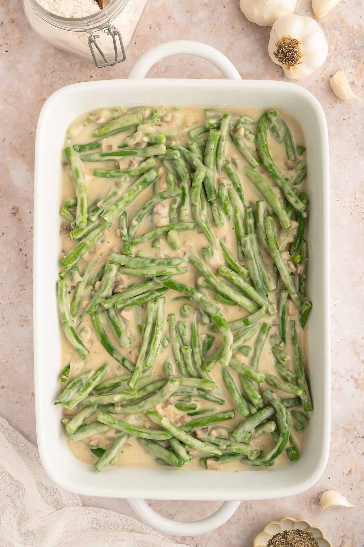Steamed green beans mixed with a creamy mushroom sauce in a casserole dish.