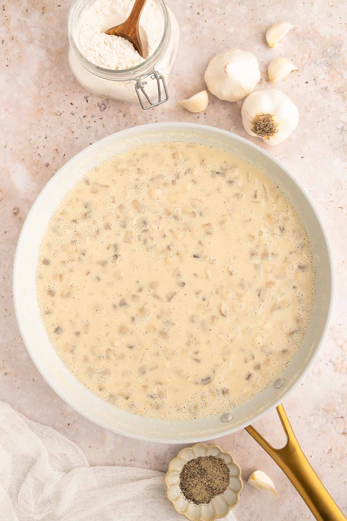 The cashew broth mixture added to the mushroom roux in the pan.